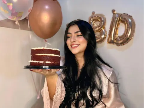 LyssaSunnyy — LyssaSunnyy holds a red velvet cake on a plate, smiling with long black hair and a pink lace robe, surrounded by rose gold balloons.