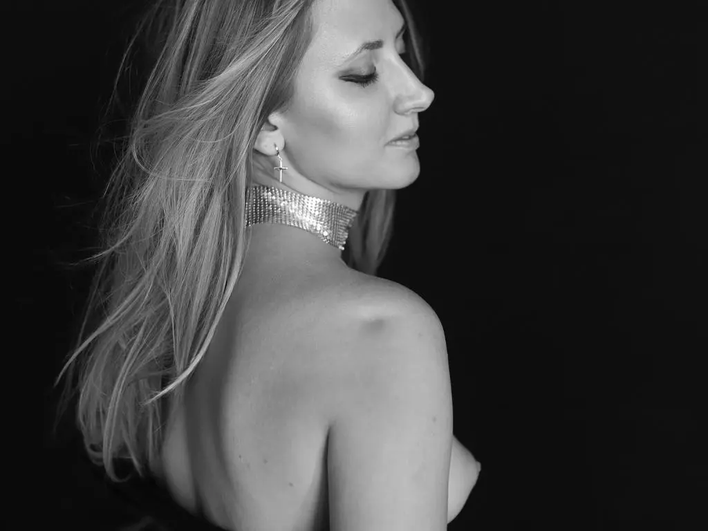 Elegant woman in a silver mesh choker posing in a moody black and white studio portrait.