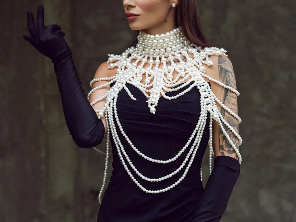 AngieShae — Elegant woman in a black dress and long gloves wearing a dramatic statement pearl necklace and body chain.