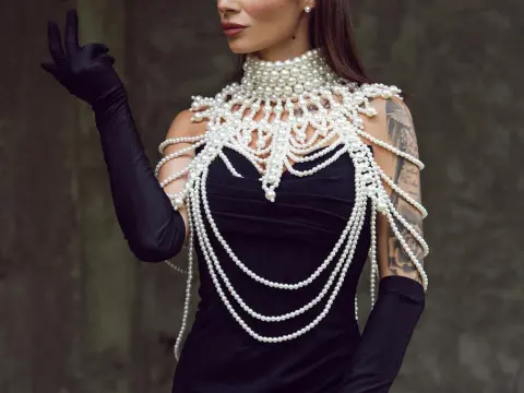 AngieShae — Elegant woman in a black dress and long gloves wearing a dramatic statement pearl necklace and body chain.