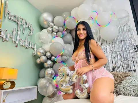 DesireLoww — Smiling woman in a pink lace outfit celebrating her 23rd birthday with silver and white balloons.
