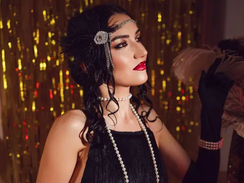 Glamorous woman in vintage 1920s flapper outfit with pearl jewelry and feathered headpiece against gold backdrop.