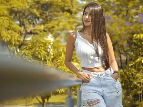 AntonelaDreamss — Young woman in a white crop top and denim shorts smiling in a sunny outdoor park setting.