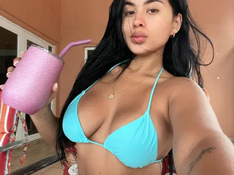Young woman in a blue bikini holding a pink mate cup on a sunny patio.