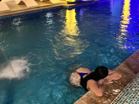 NicoleCruz_ — NicoleCruz_ wears a blue bikini while lounging at the edge of a lit swimming pool at night.