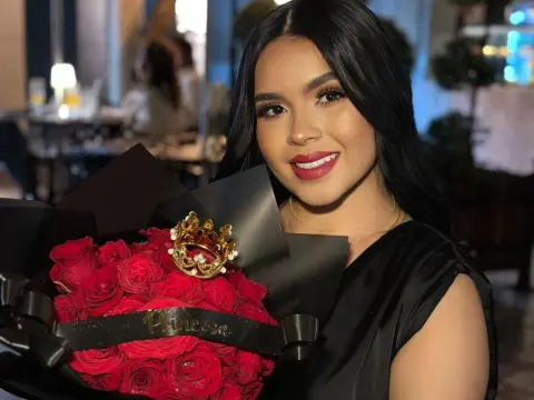NicoleCruz_ — NicoleCruz_ smiles while holding a large bouquet of red roses wrapped in black paper.