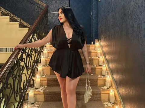 NicoleCruz_ — NicoleCruz_ wears a black satin romper while standing on a staircase lined with lit candles.