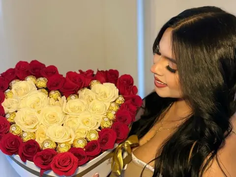 NicoleCruz_ — NicoleCruz_ smiles while holding a large heart-shaped box filled with white roses and gold-wrapped chocolates.