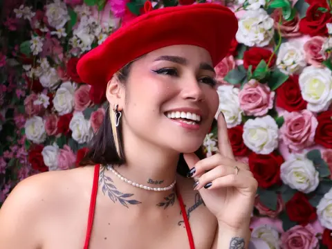 LaurenWard — Smiling woman in a red beret and tank top posing against a romantic pink and white rose flower wall.