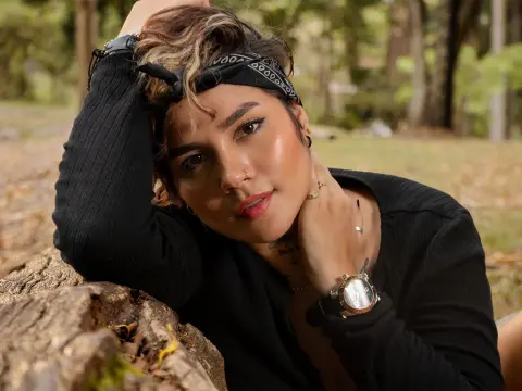 LaurenWard — Smiling woman in a black long-sleeve top and black bandana relaxing outdoors in a sunny forest setting.