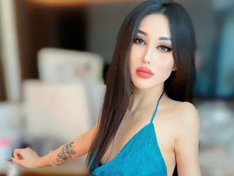 LaLissaGirl poses with long black hair, wearing a blue sparkly halter top and showing a tattoo on her arm.