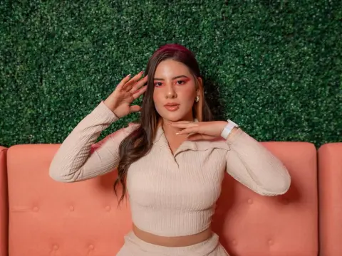 Stylish woman in a cream ribbed knit outfit posing confidently against a lush green hedge background.