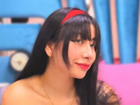 Andromeda_ — Smiling young woman with long dark hair and red headband in a bright, colorful indoor setting.