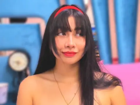 Andromeda_ — Smiling young woman with long black hair and red headband in a bright, colorful indoor setting.