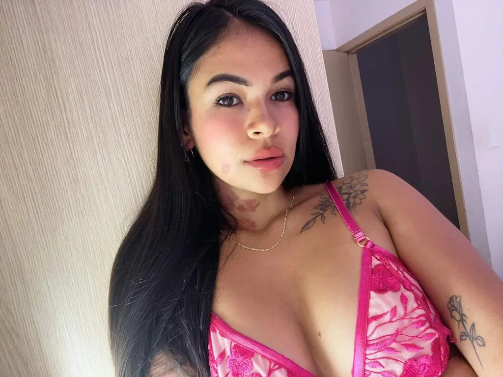 LaraTaylor — Young woman with long dark hair wearing a pink floral bikini top in a bright indoor setting.