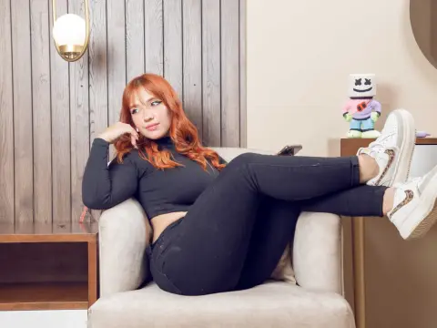 Sweet_Sandy — Redheaded woman in black crop top and jeans relaxing in a modern living room setting.