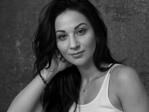 Kethlyne — Smiling young woman with long dark hair wearing a white tank top against a textured grey background.