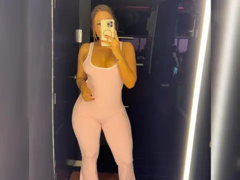 Rousehot — Rousehot poses in a mirror wearing a tight, light pink tank-top bodysuit that shows off her cleavage and curves.