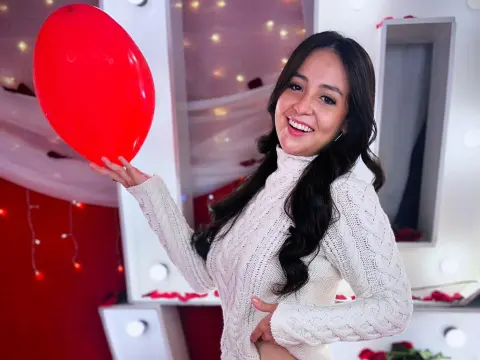 SamanthaClay — Smiling woman in a white cable-knit turtleneck sweater celebrating in a festive room with a red balloon.