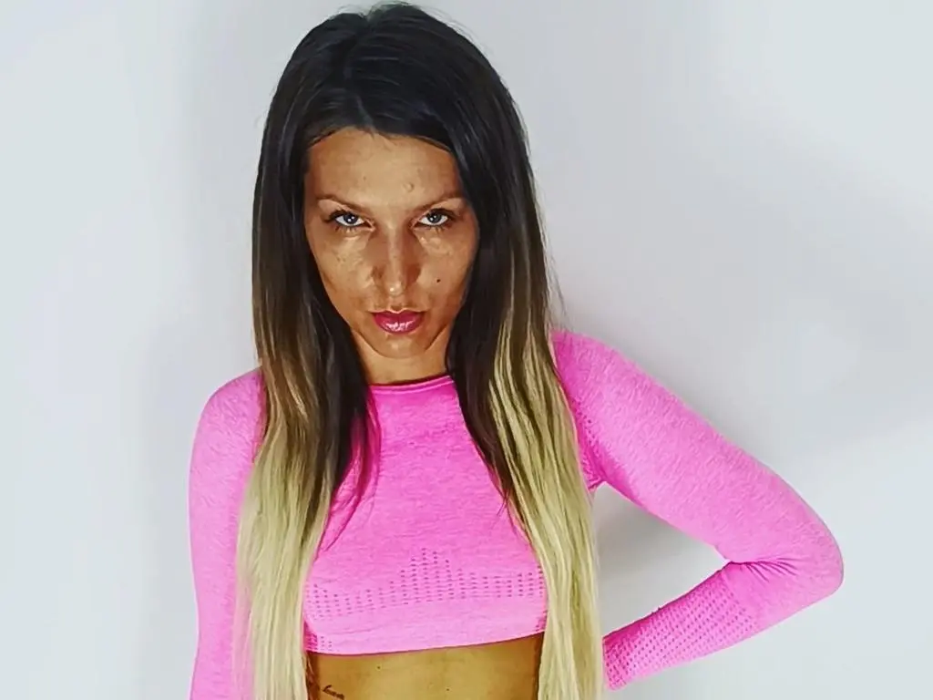 GlamyGlamour91 — Confident woman in a pink long-sleeve crop top posing against a white background.