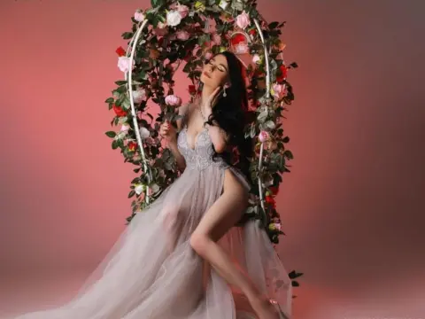 NorraJoice — NorraJoice sits in a floral swing wearing a sheer grey lace gown with a high slit.