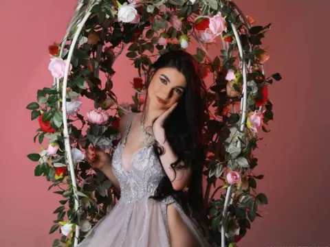 NorraJoice — NorraJoice poses in a silver lace dress inside a floral swing against a pink background.
