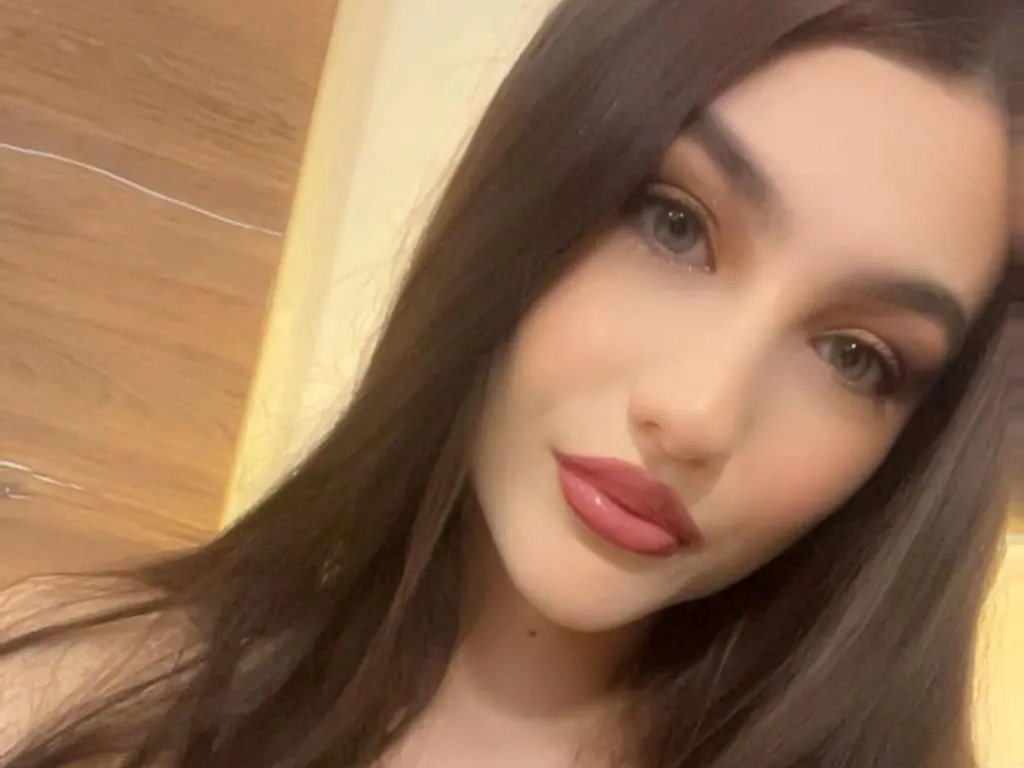 NorraJoice — NorraJoice looks into the camera with long dark hair and pink lipstick.