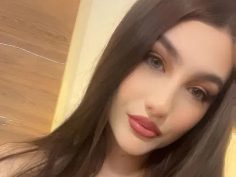 NorraJoice — NorraJoice looks into the camera with long dark hair and pink lipstick.