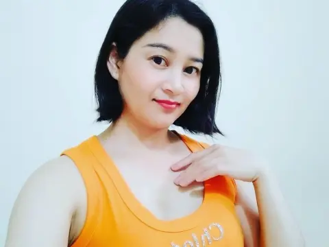 NaughtyAnna — Smiling woman in an orange tank top posing against a plain white background for a bright portrait.