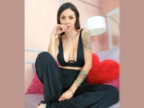 Mix_Kitty — Young woman in a black crop top and trousers sitting relaxed on a sofa in a bright room.