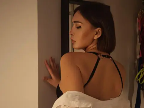 emm_quince — Young woman in a black halter top posing in a dimly lit room with a moody, cinematic atmosphere.