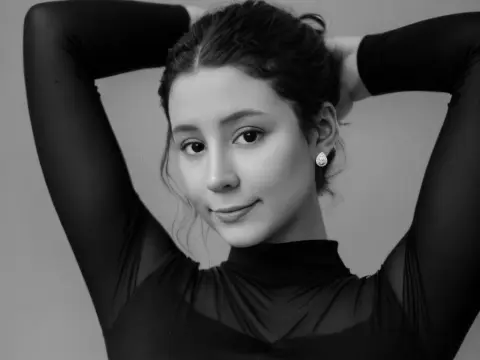 SweetTulip — Portrait of a smiling young woman in a black turtleneck top posing against a plain studio background.