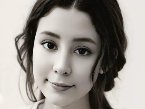 SweetTulip — Close-up portrait of a young woman with dark wavy hair and a serene expression against a neutral background.