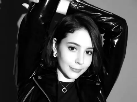 SweetTulip — Stylish young woman in a black leather jacket posing with a confident expression in a black and white portrait.