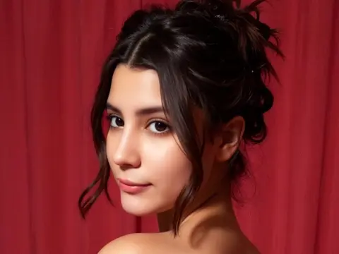 SweetTulip — Young woman with wavy dark hair and natural makeup posing against a red velvet curtain background.