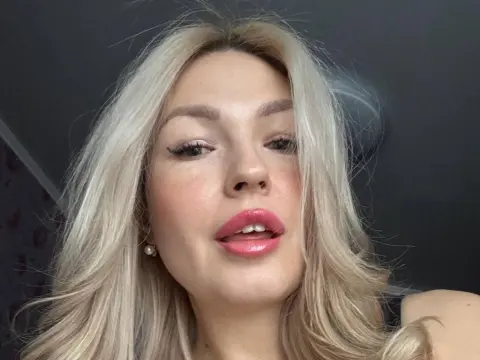 HelenOneLove looks into the camera with long blonde hair and pink lipstick in a close-up selfie.