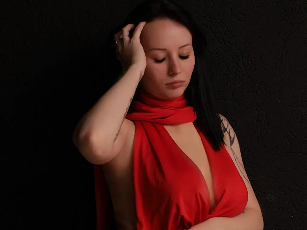 Moody portrait of a woman in a red silk halter dress against a dark textured background.