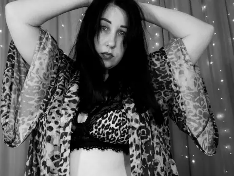 Moody black and white portrait of a woman in a leopard print kimono and lace bra against fairy lights.