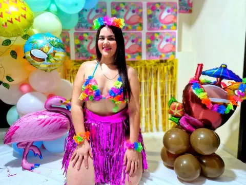 Smiling woman in a colorful floral bikini and pink grass skirt at a tropical flamingo themed birthday party.