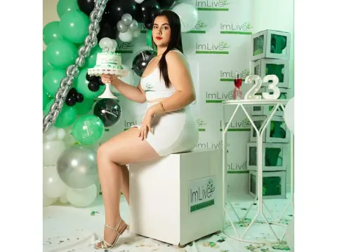 Young woman in a white outfit celebrating her birthday with cake and green balloons in a festive setting.