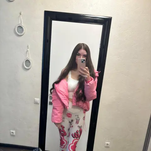 alicaangel007 — alicaangel007 poses for a mirror selfie wearing a pink puffer jacket and white patterned leggings with her long brown hair down.
