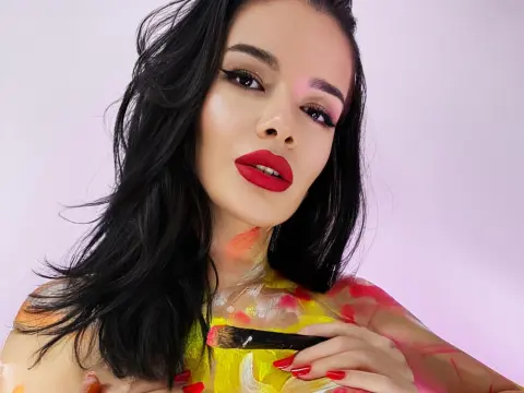 Artistic woman with red lipstick and colorful body paint posing against a soft pink background.