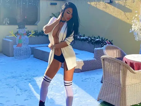 AlexxxaPower — Slim woman in a white robe and black lingerie posing in a snowy outdoor patio setting.