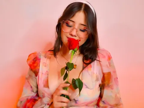 ImSophiaa222 — Dreamy portrait of a woman in a floral dress holding a red rose against a pink background.