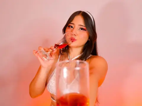 ImSophiaa222 — Young woman in white lace top sipping rose wine against a soft pink background in a romantic mood.