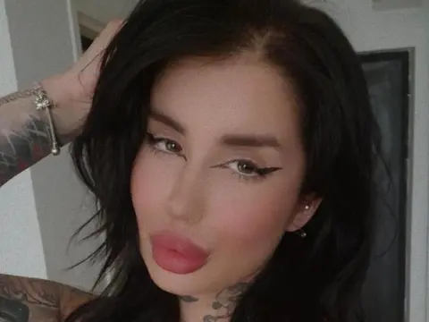 MallorieFoxx poses with her black hair and winged eyeliner, showing off her tattoos and full pink lips.
