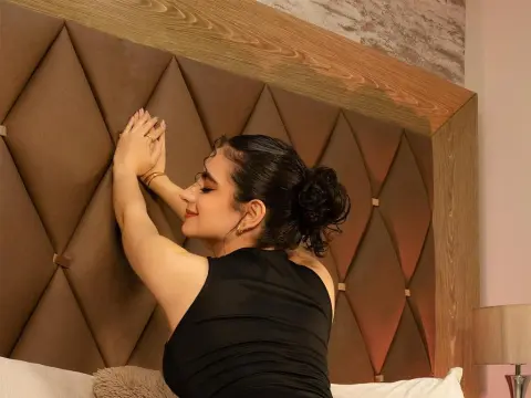 Relaxed woman in a black dress stretching against a luxury tufted headboard in a cozy bedroom setting.