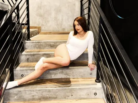 LaraHarvey sits on concrete stairs wearing a white long-sleeve bodysuit and white socks, showing her bare legs and smooth skin.