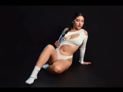 Sophie_Winslow poses sitting on a black floor wearing a white cutout long-sleeve crop top and matching white undies with white socks.