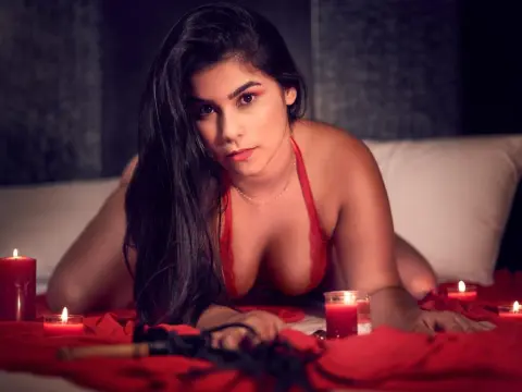 Princes_Jasmine — Princes_Jasmine lies on a bed in red lingerie, looking at the camera with long dark hair and candles glowing around her.
